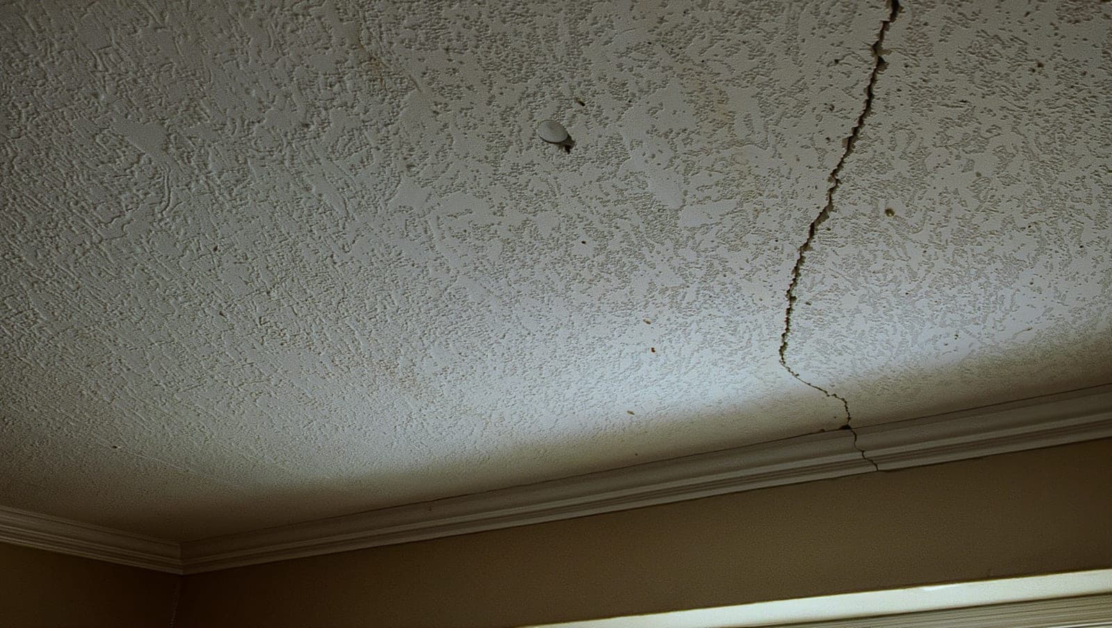 Long crack running across a textured ceiling